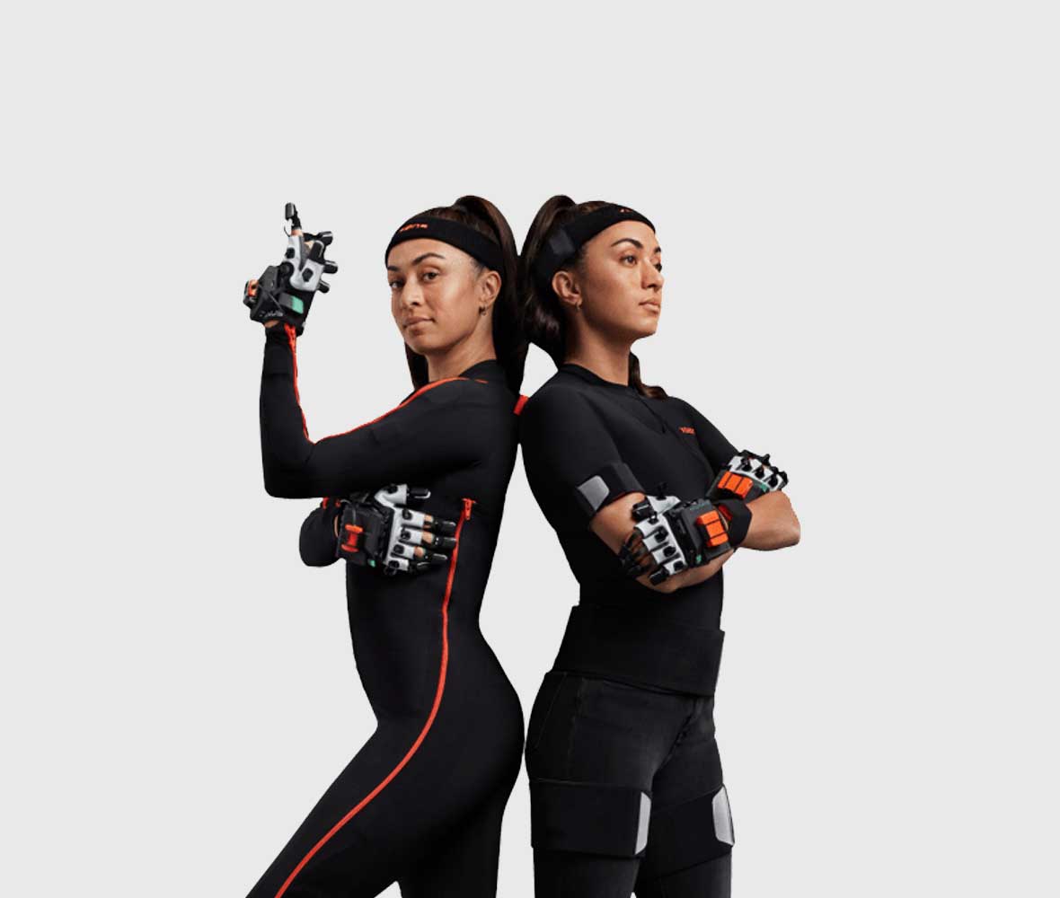 Two women Back 2 back wearing motion capture suits and gloves